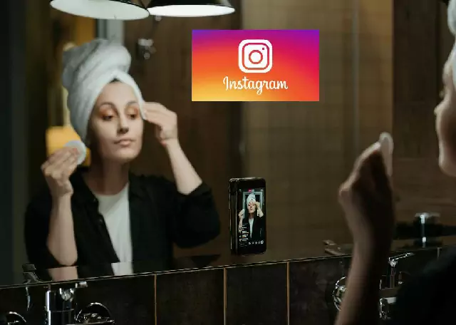 Mulher se maquiando na frente de um grande espelho na frente de um celular preso a um tripé e na parte superior uma imagem com o ícone do instagram.