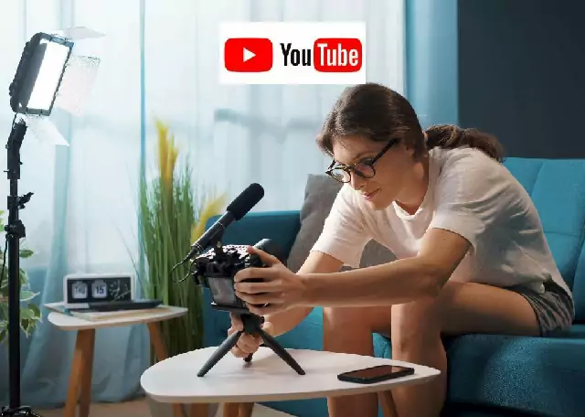 Em um ambiente de sala uma mulher sentada no sofá posicionando câmera e microfone em cima da mesinha de centro, acima de sua cabeça está a logo do Youtube.